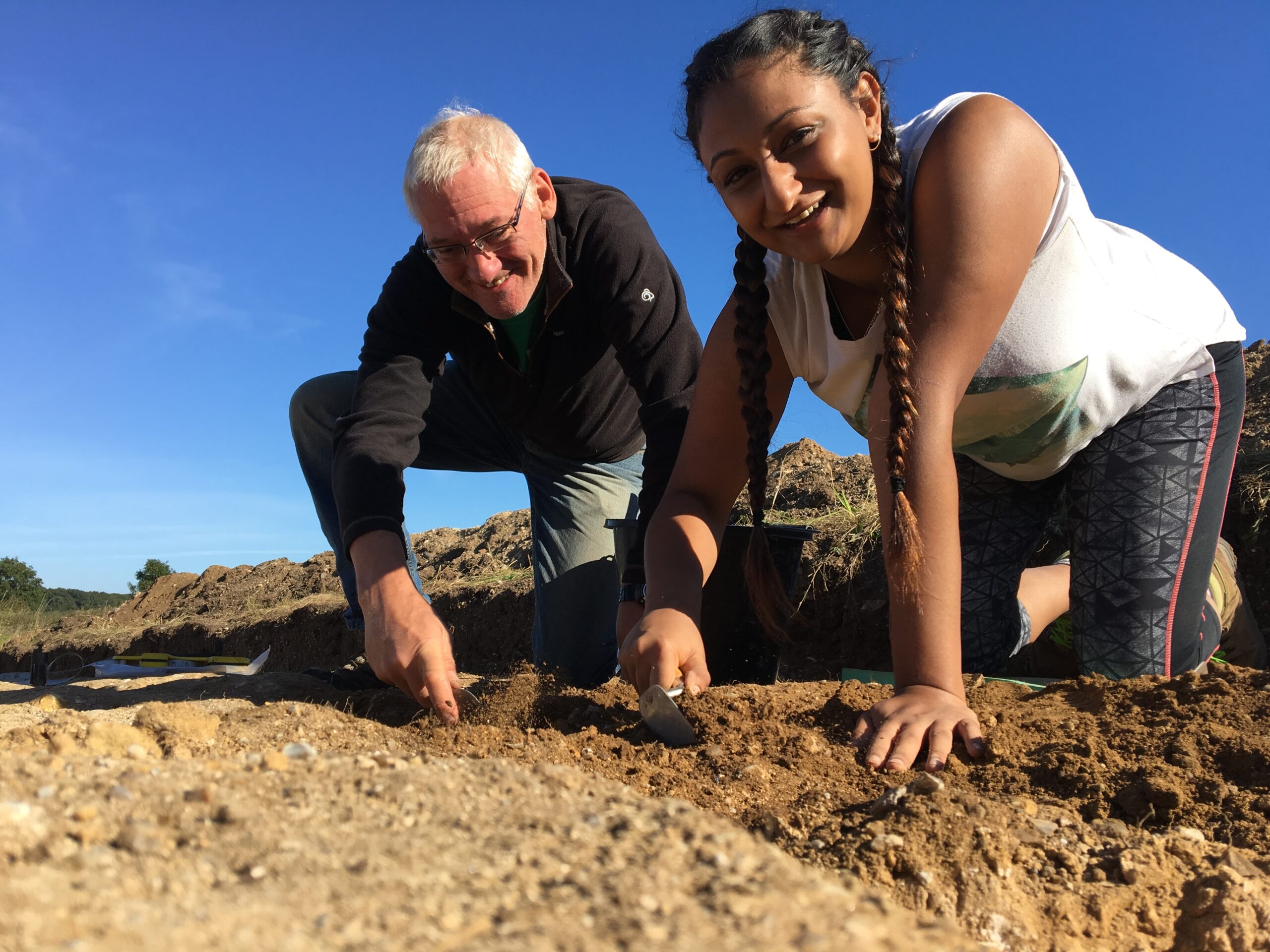 Man and girl in a archaeological dig trench digging