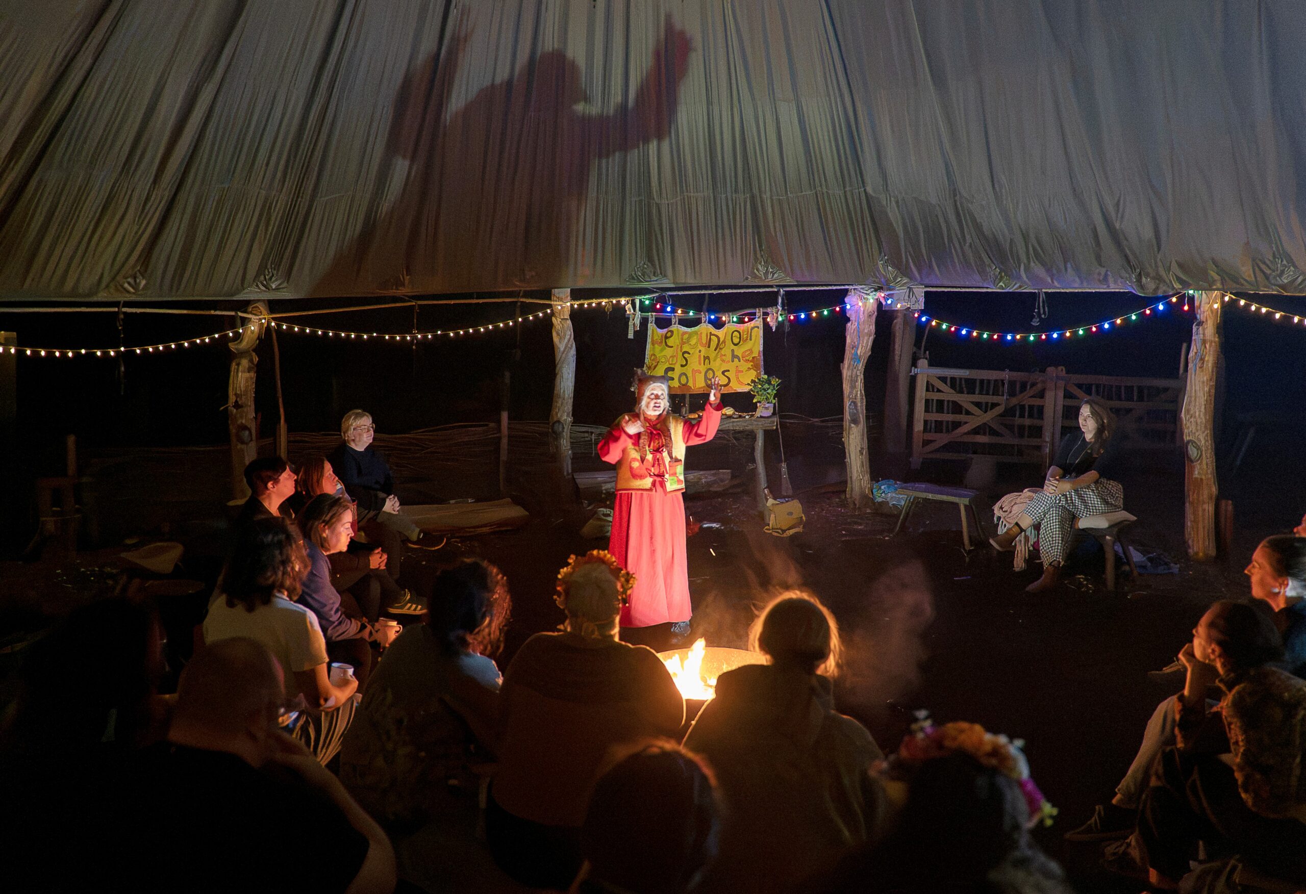Lady by a fire standing up telling stories
