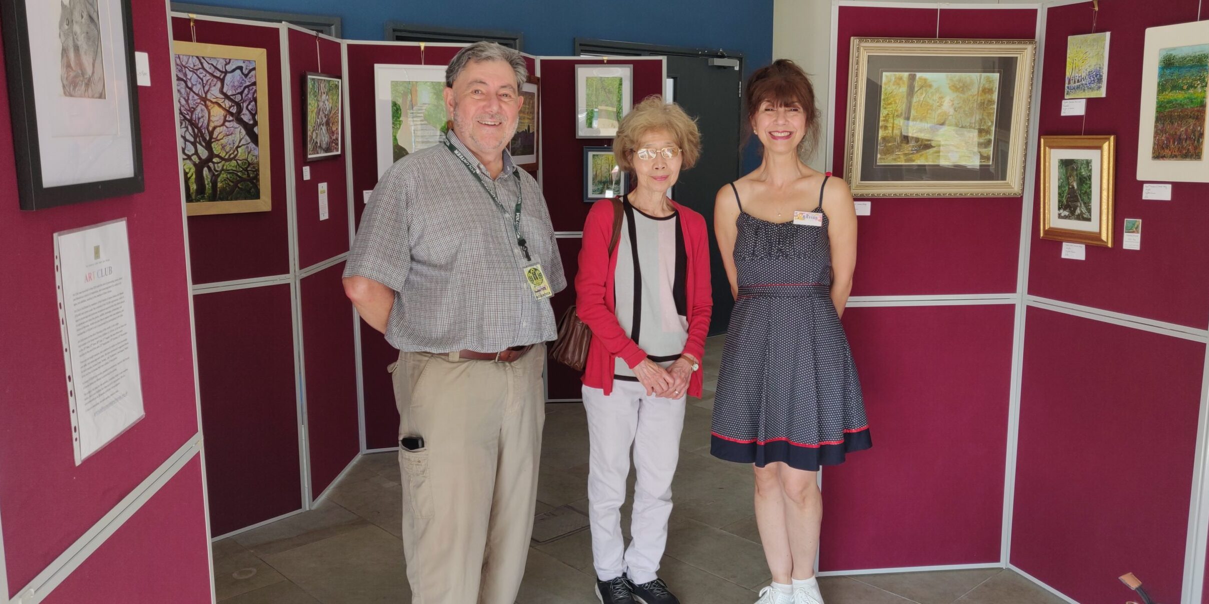 3 adults standing in front of an art exhibition