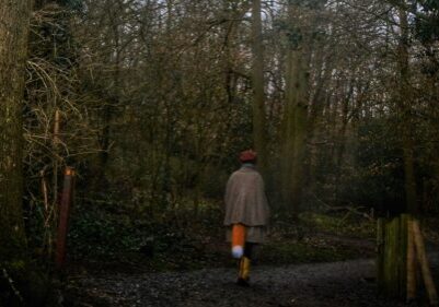 Lady wearing a fox tail walking through the woods